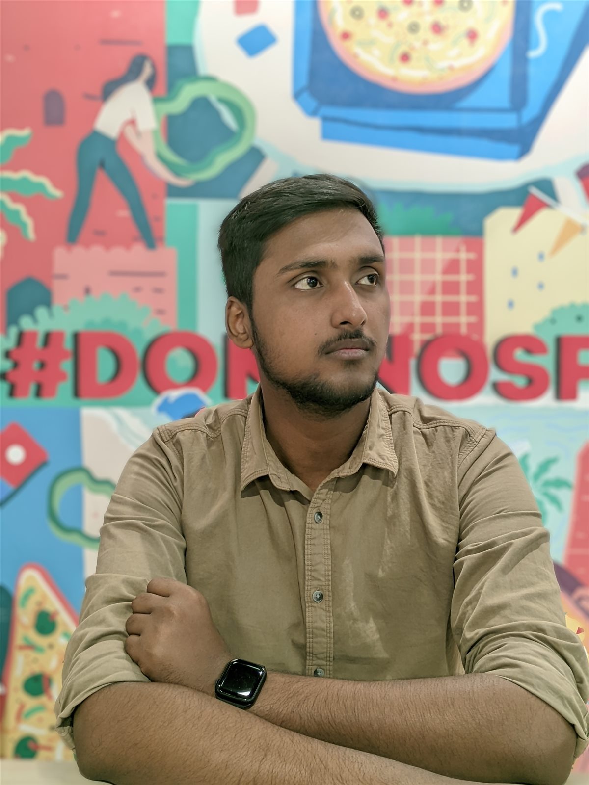 Vishwas Jha seated in front of a colourful mural wall